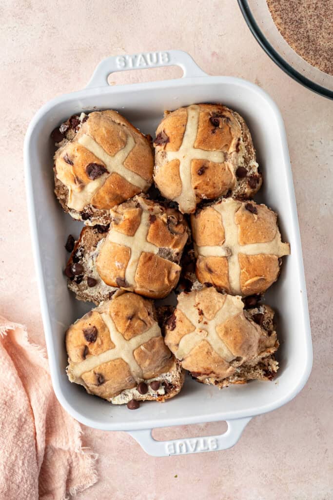 Arranging the buttered hot cross buns in the baking dish.
