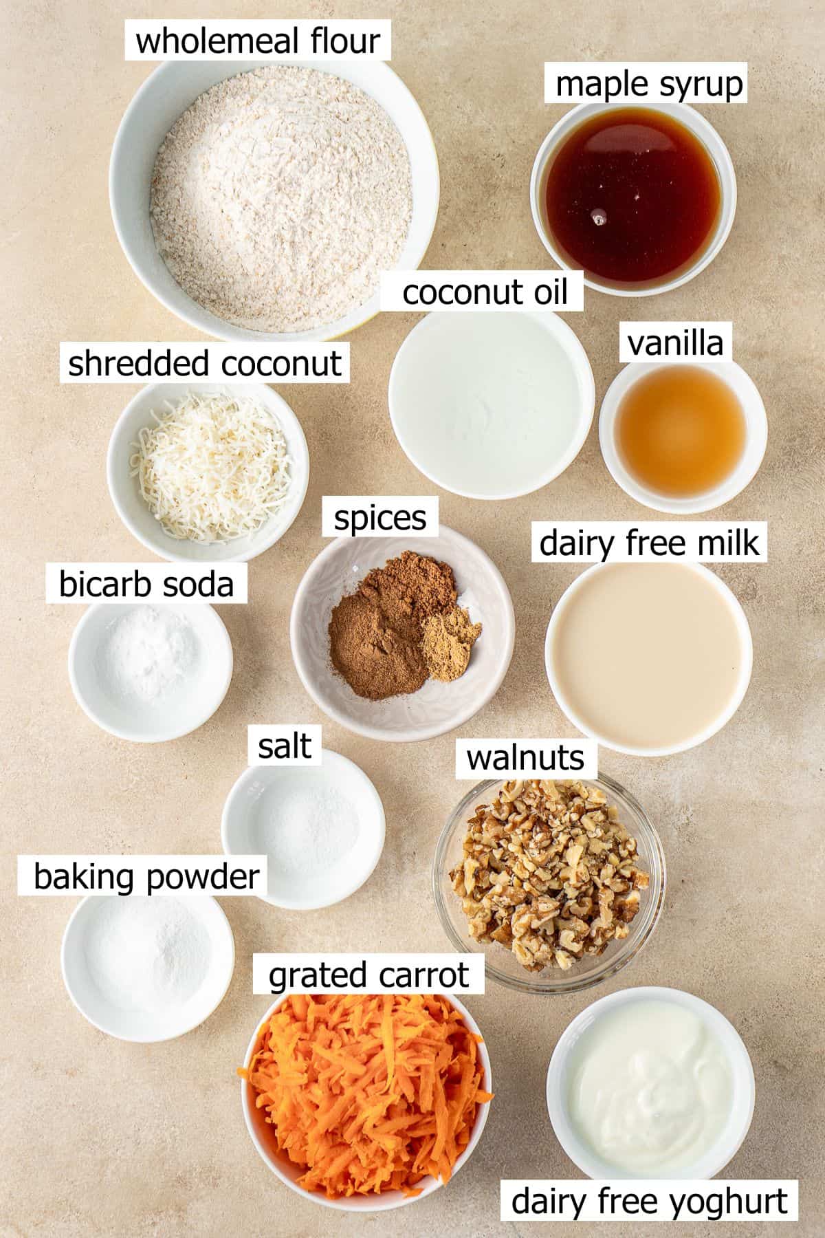 All ingredients needed to make vegan carrot cake muffins laid out in small bowls.