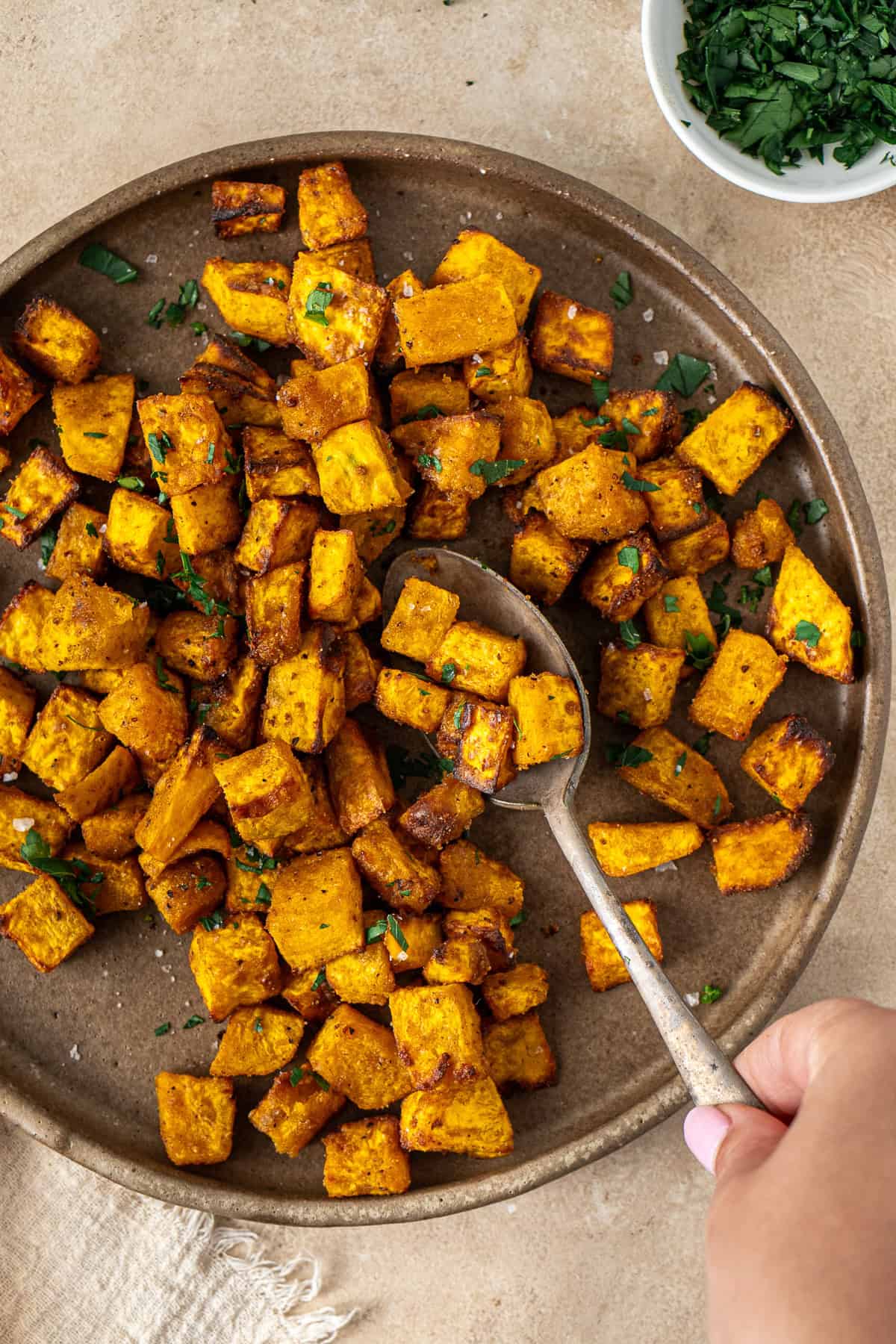 A hand spooning some pumpkin from the serving plate.