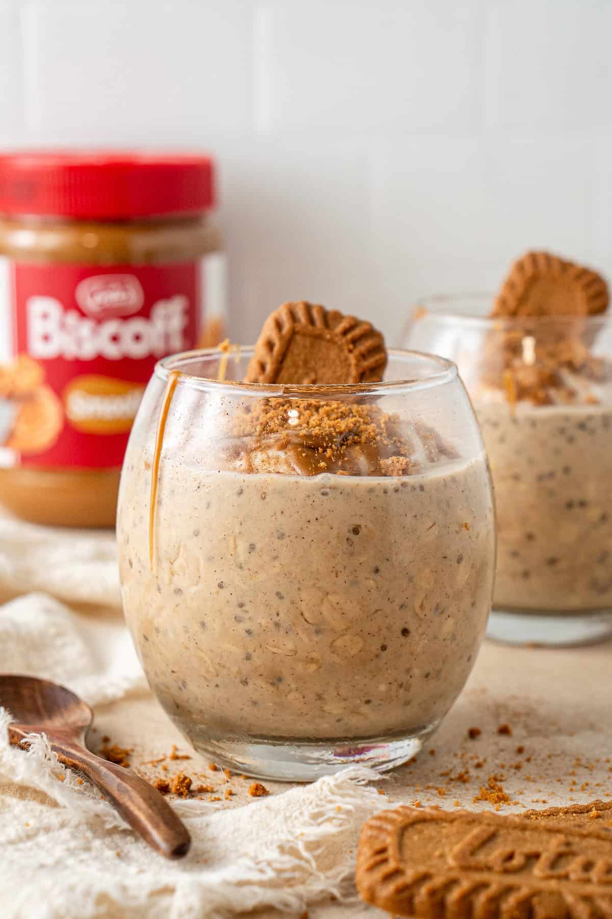 Close up of biscoff overnight oats in a glass with a biscoff cookie on top.