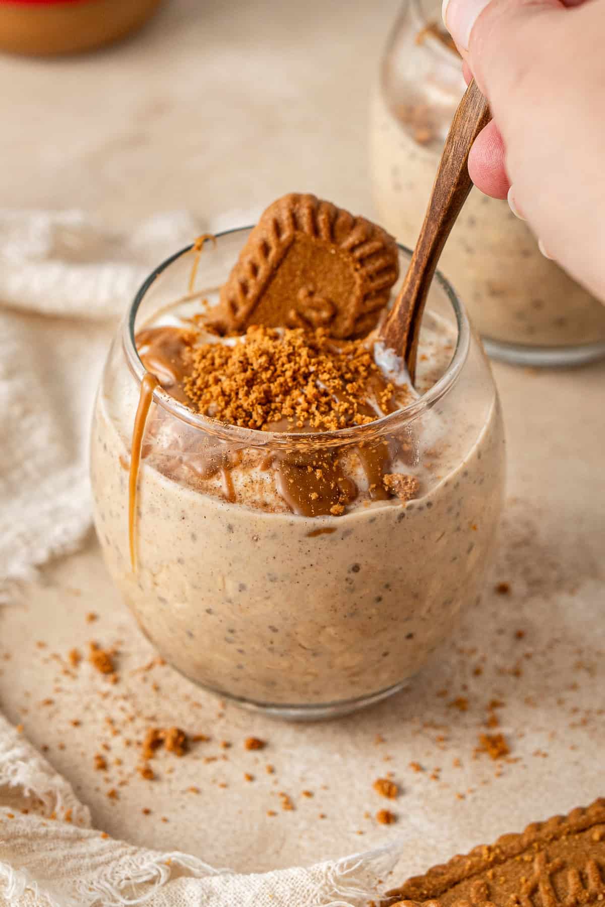 A spoon scooping out biscoff overnight oats from a jar.