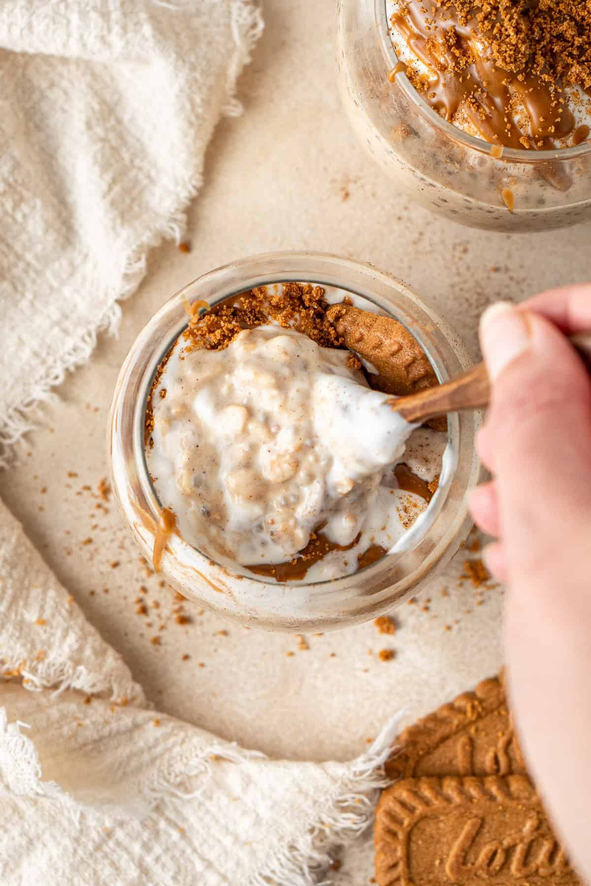 A hand with a spoon take a scoop of the oats from the glass.