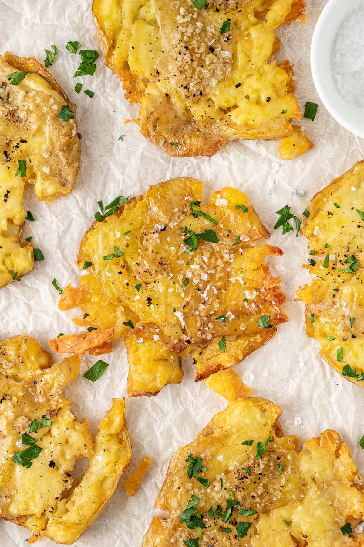 Close up of a crispy smashed potato with parsley and flaky sea salt.