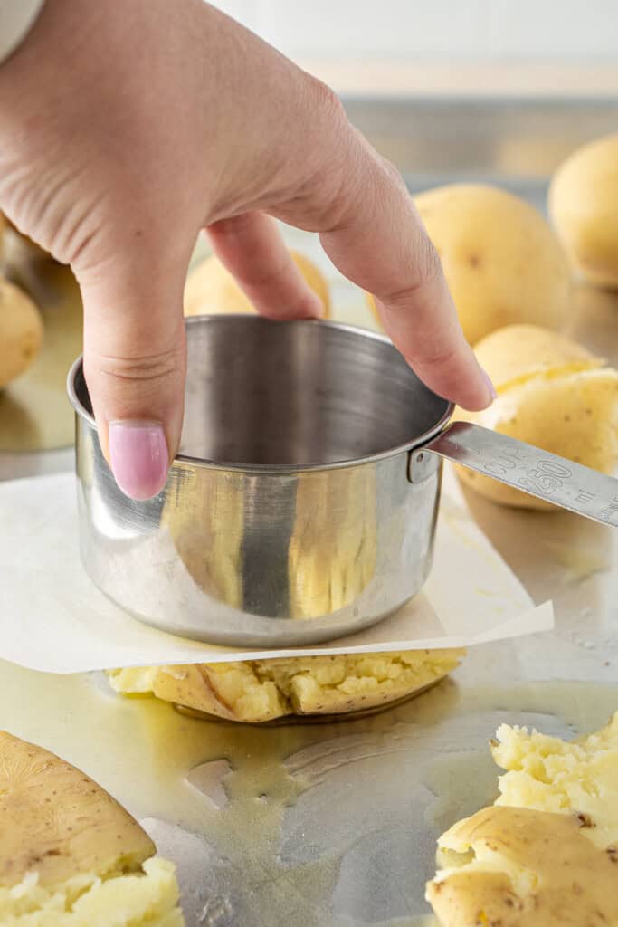 Smashing the potatoes using a measuring cup.