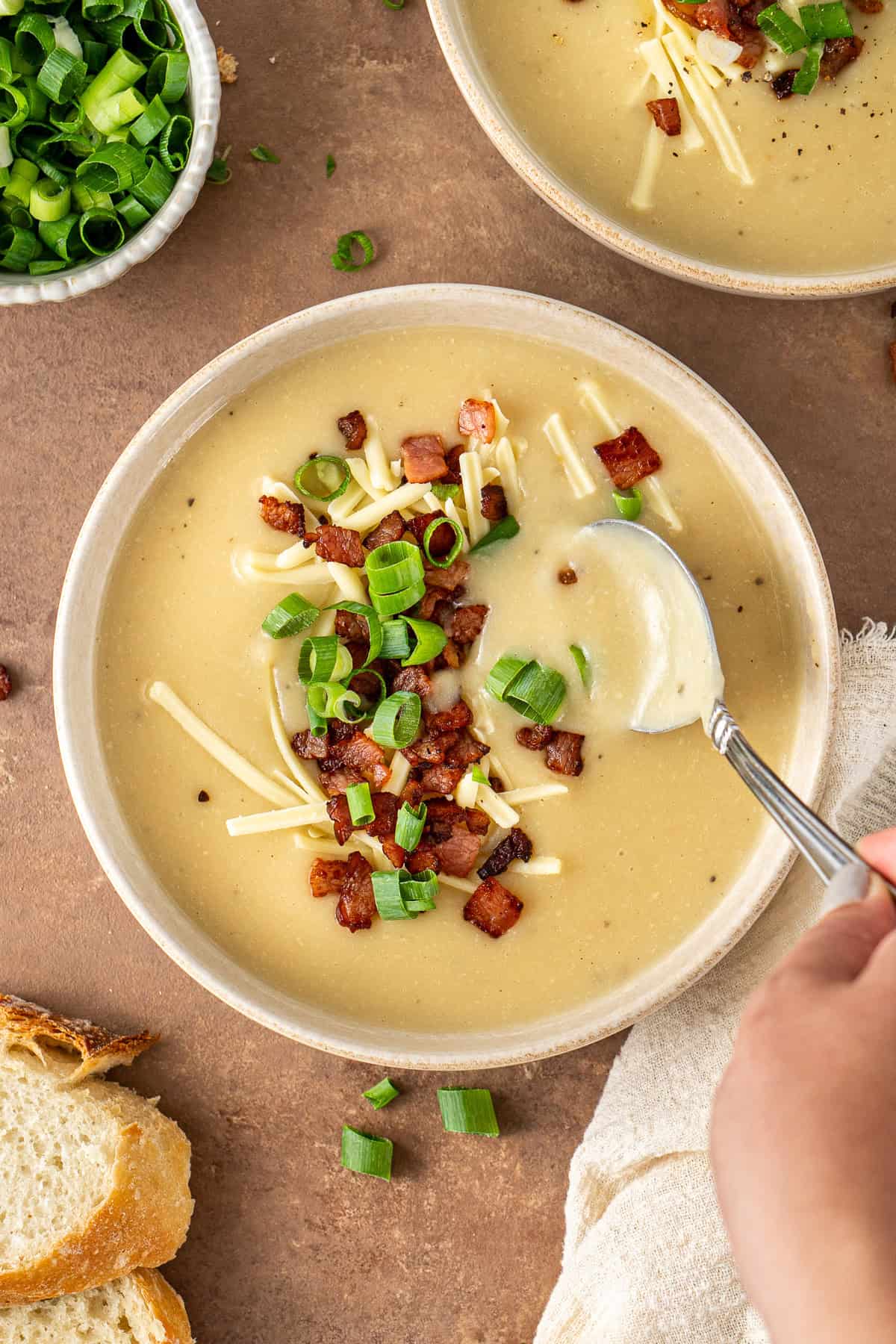 A spoon taking a bite of baked potato soup.