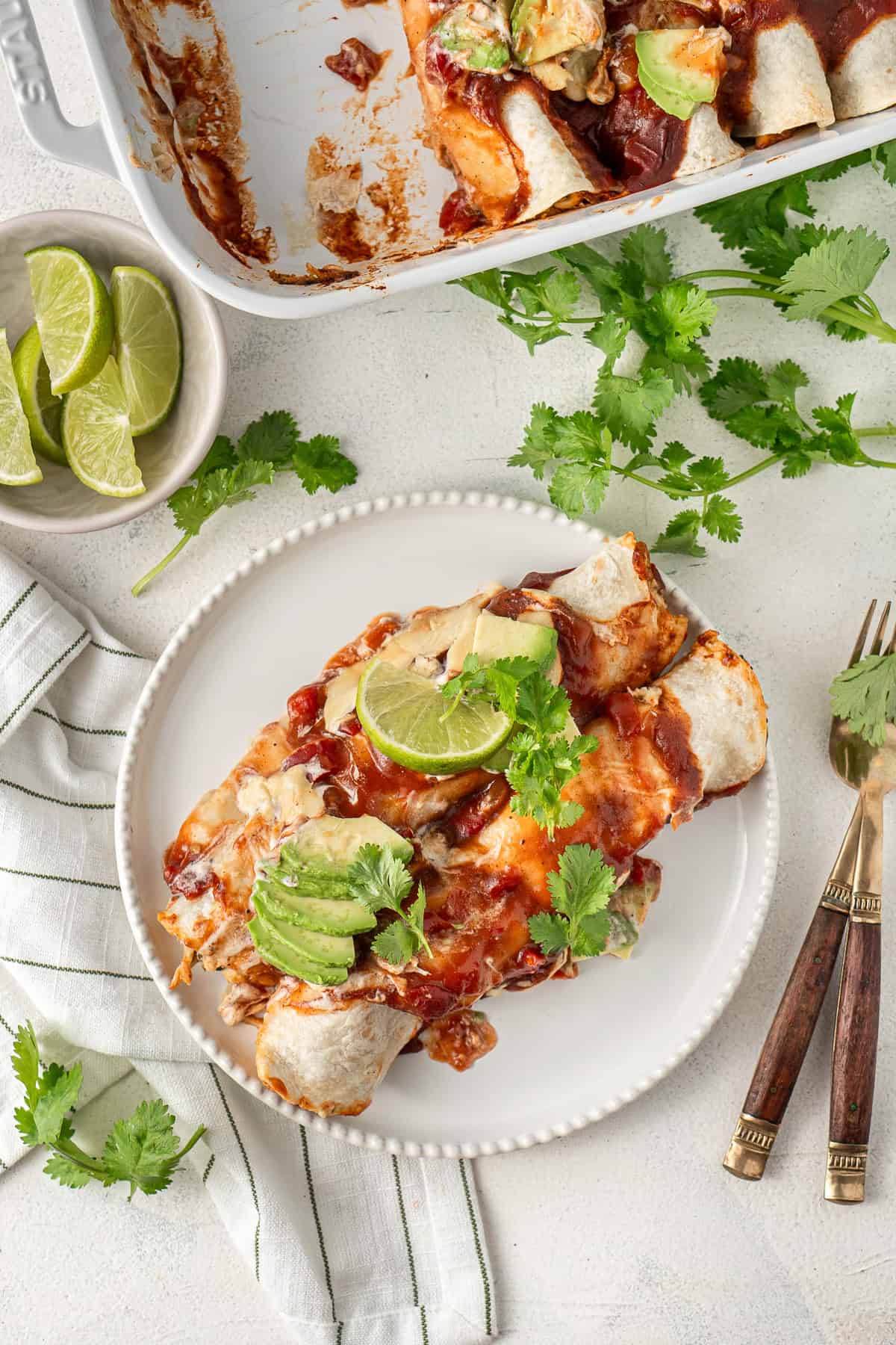 Chicken enchiladas served onto a plate with coriander. 