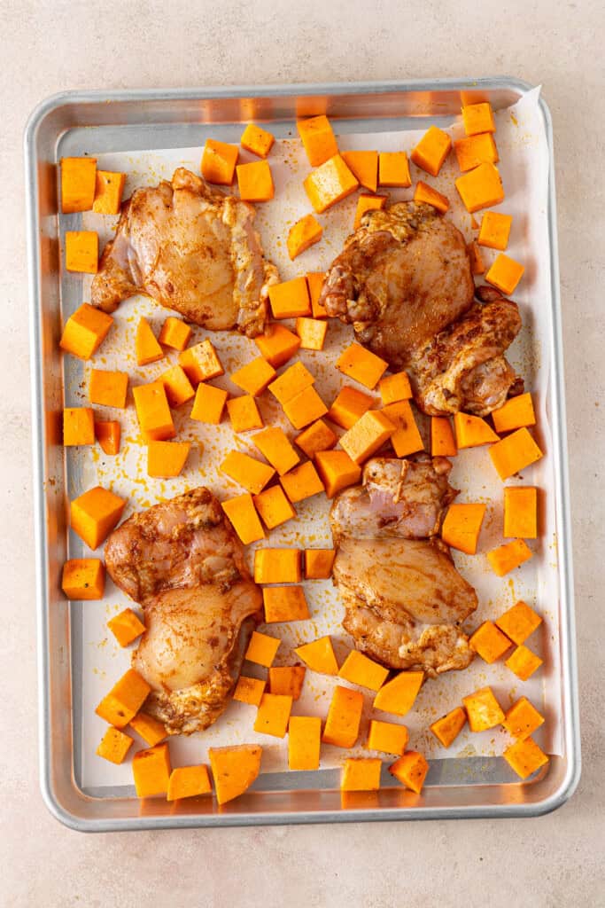 The raw sweet potato and chicken on a baking tray.