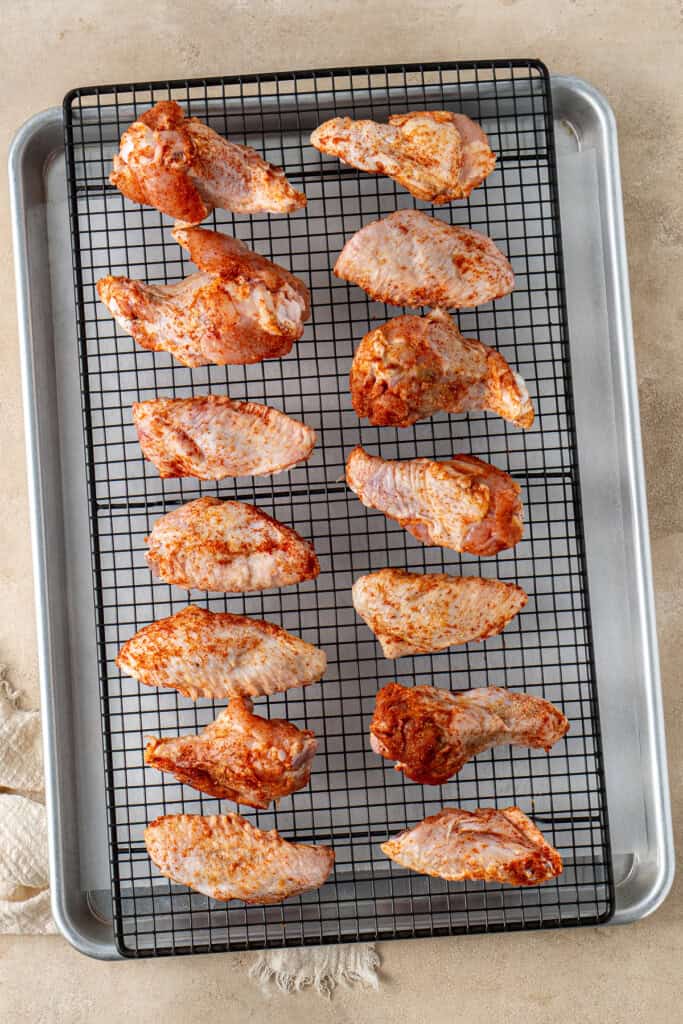 The spiced chicken wings on a wire rack on a tray.
