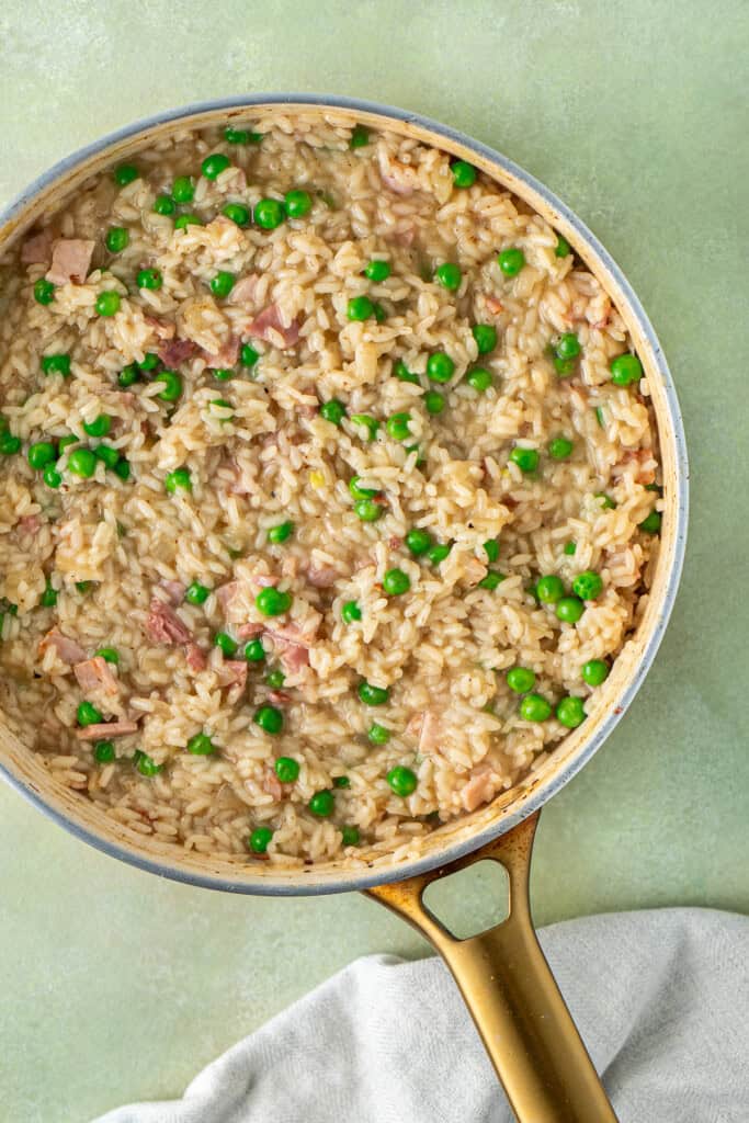 The finished risotto in the pan with bacon and peas.