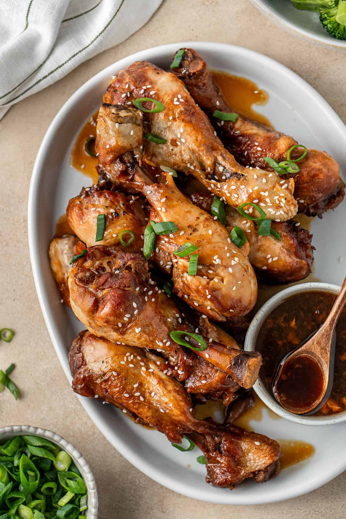 Chicken drumsticks on a platter with sauce.