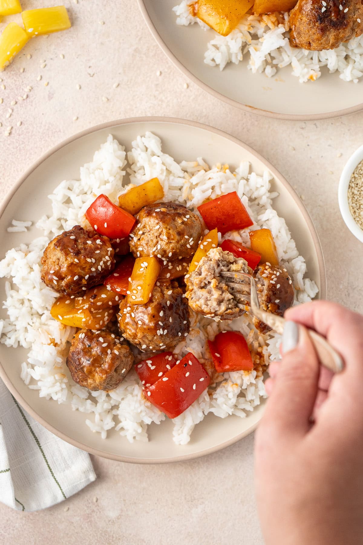 A hand taking a bite of pork meatball using a fork.