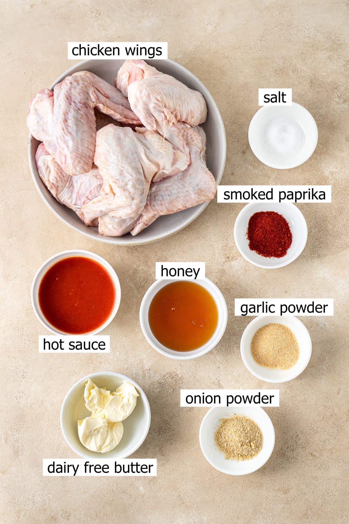 All ingredients needed to make hot honey chicken wings laid out in small bowls.
