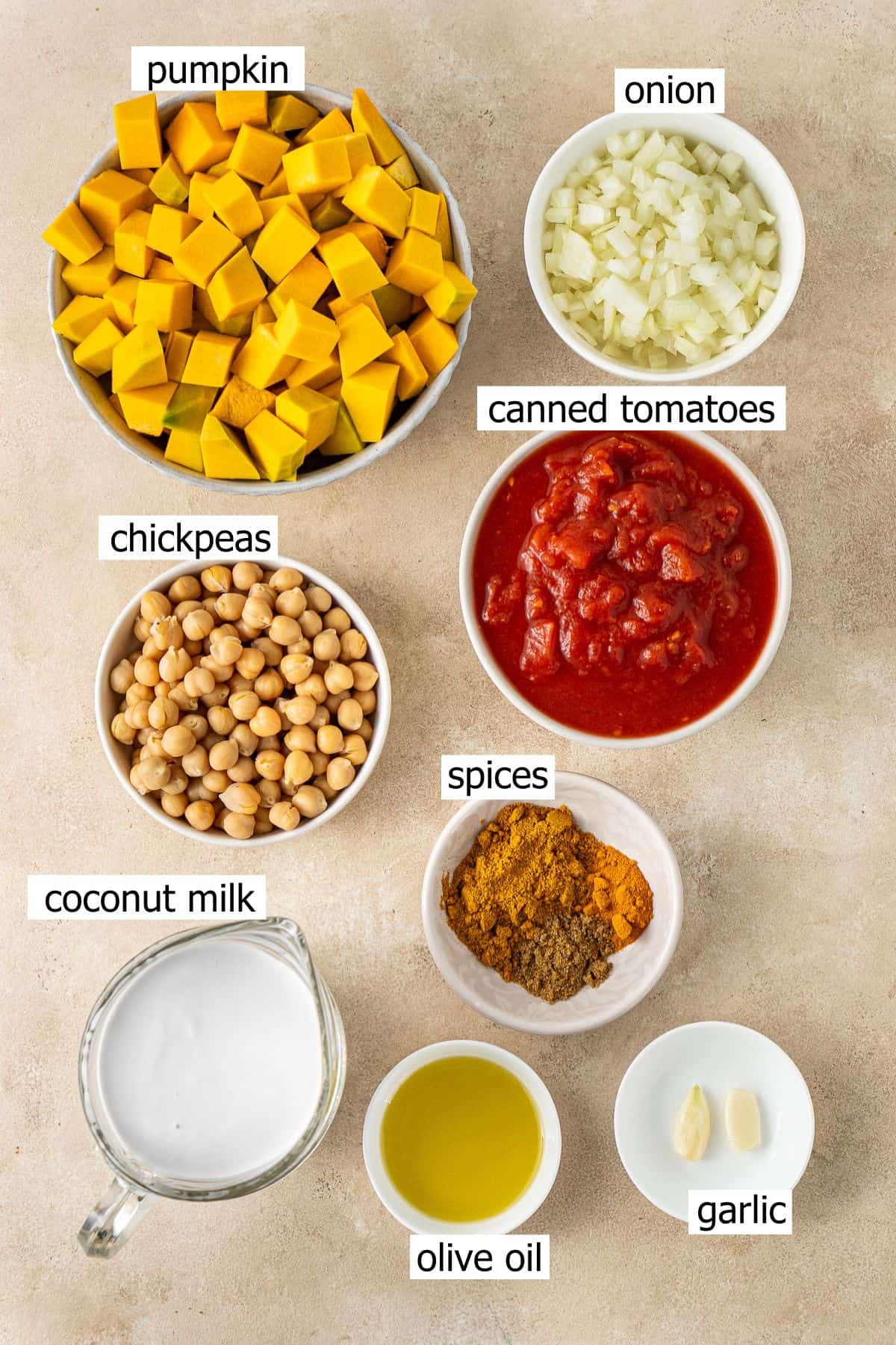 All ingredients needed to make pumpkin and chickpea curry laid out in bowls.