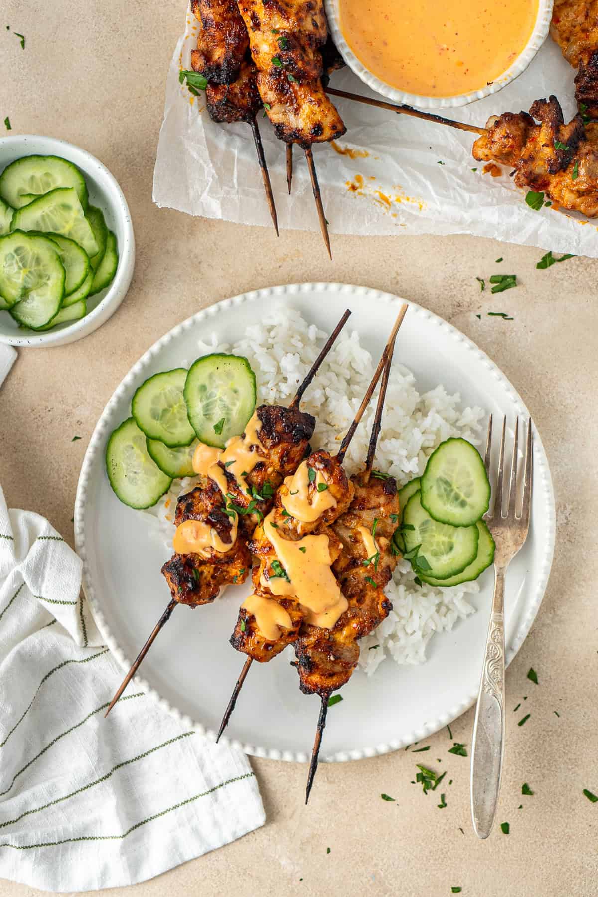 Bang bang chicken skewers served with rice and cucumber.