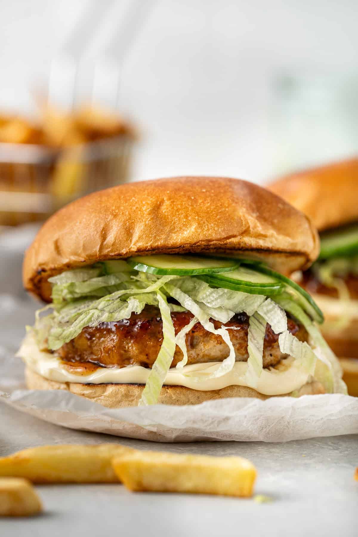Close up of a chicken teriyaki burger with lettuce and cucumber.