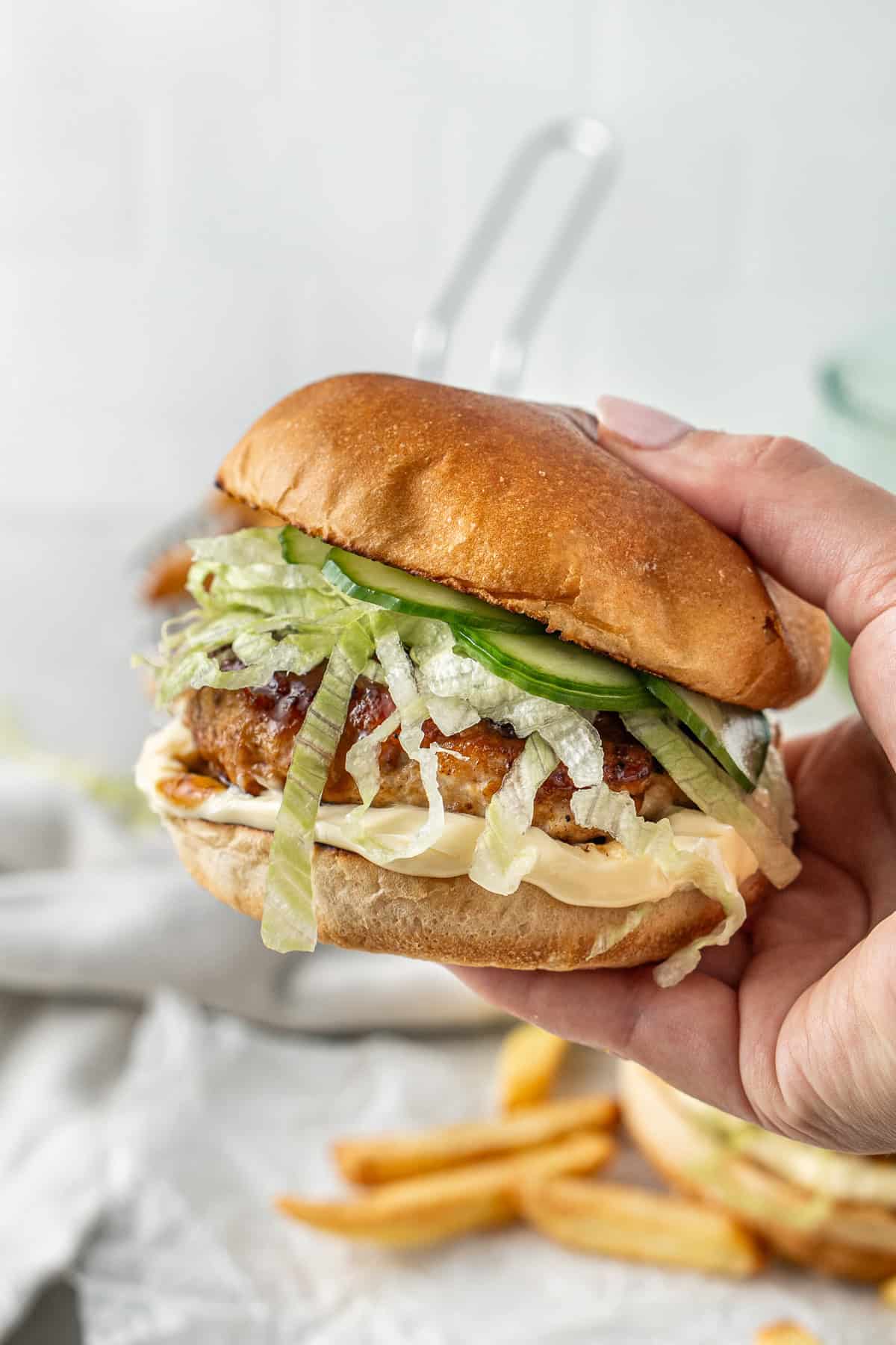 A hand holding a chicken teriyaki burger.