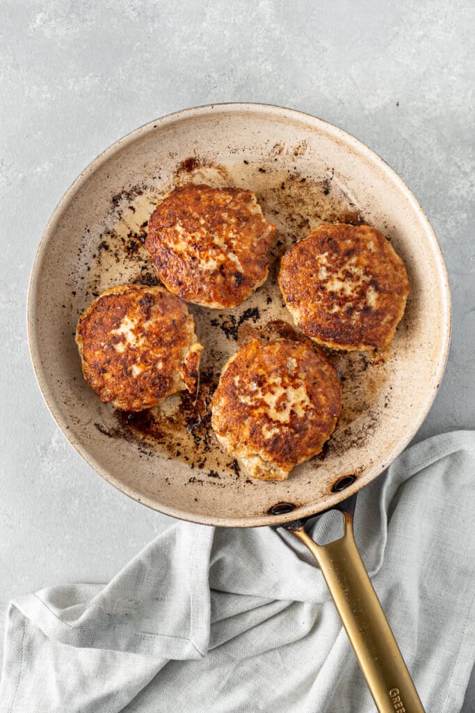 Cooked chicken patties in a frying pan.