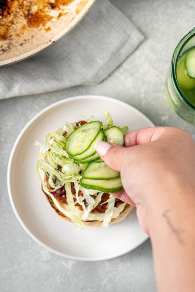 Adding the pickled cucumber to the burger.