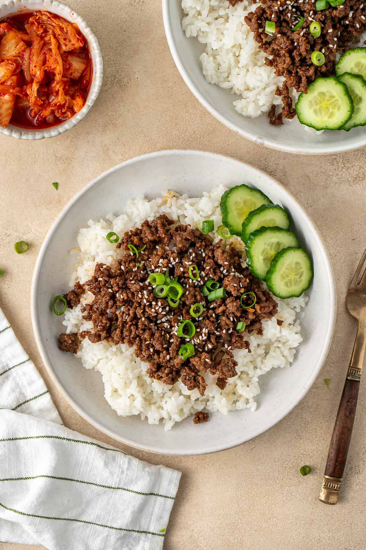 Korean beef bowl with rice and sliced cucumber.