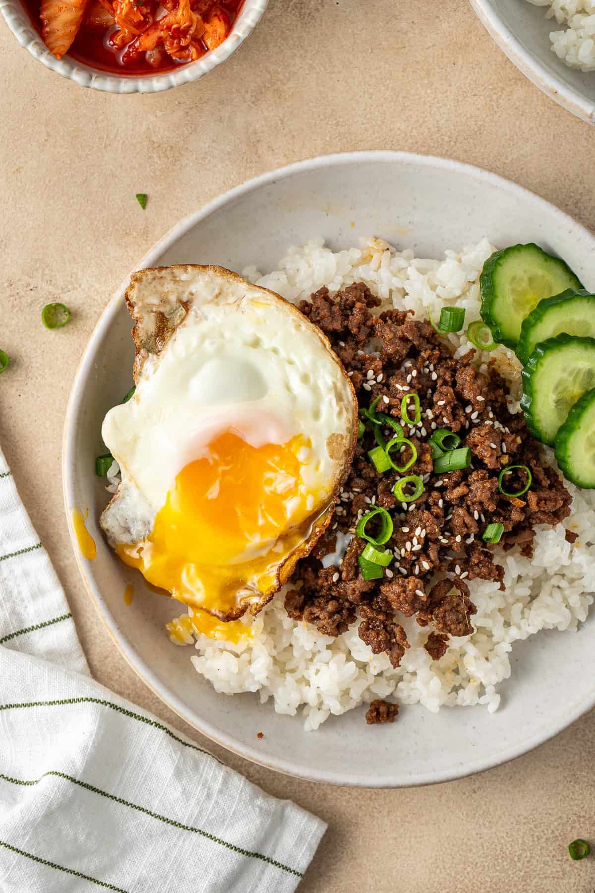 Beef and rice bowl topped with a fried egg with a broken yolk.
