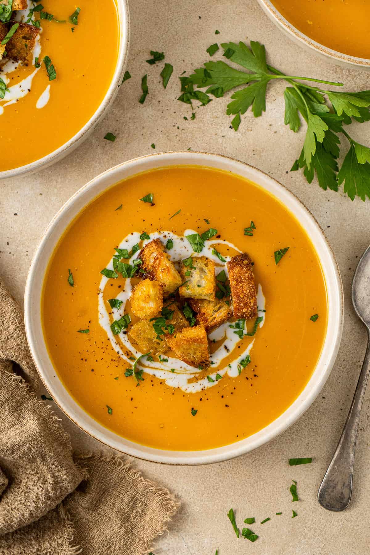 Turmeric sweet potato soup in bowls with croutons and parsley. 
