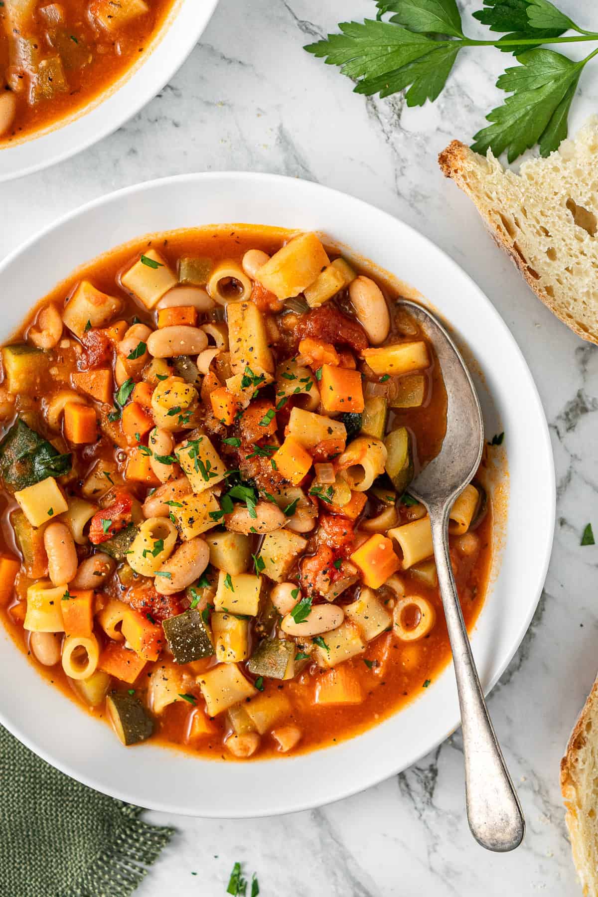 Close up of a bowl of vegetable minestrone soup with a spoon.