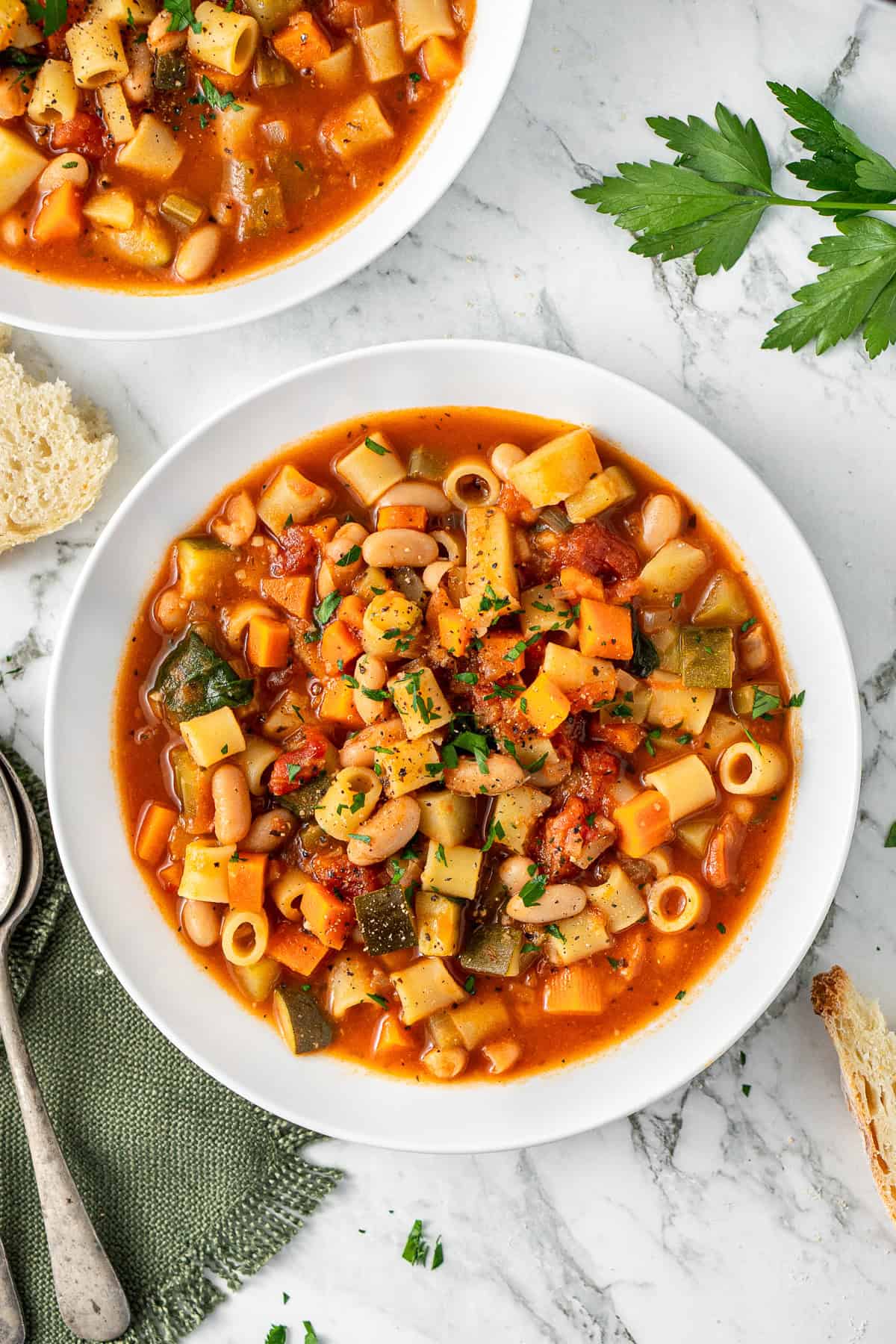 The minestrone soup served into white bowls.