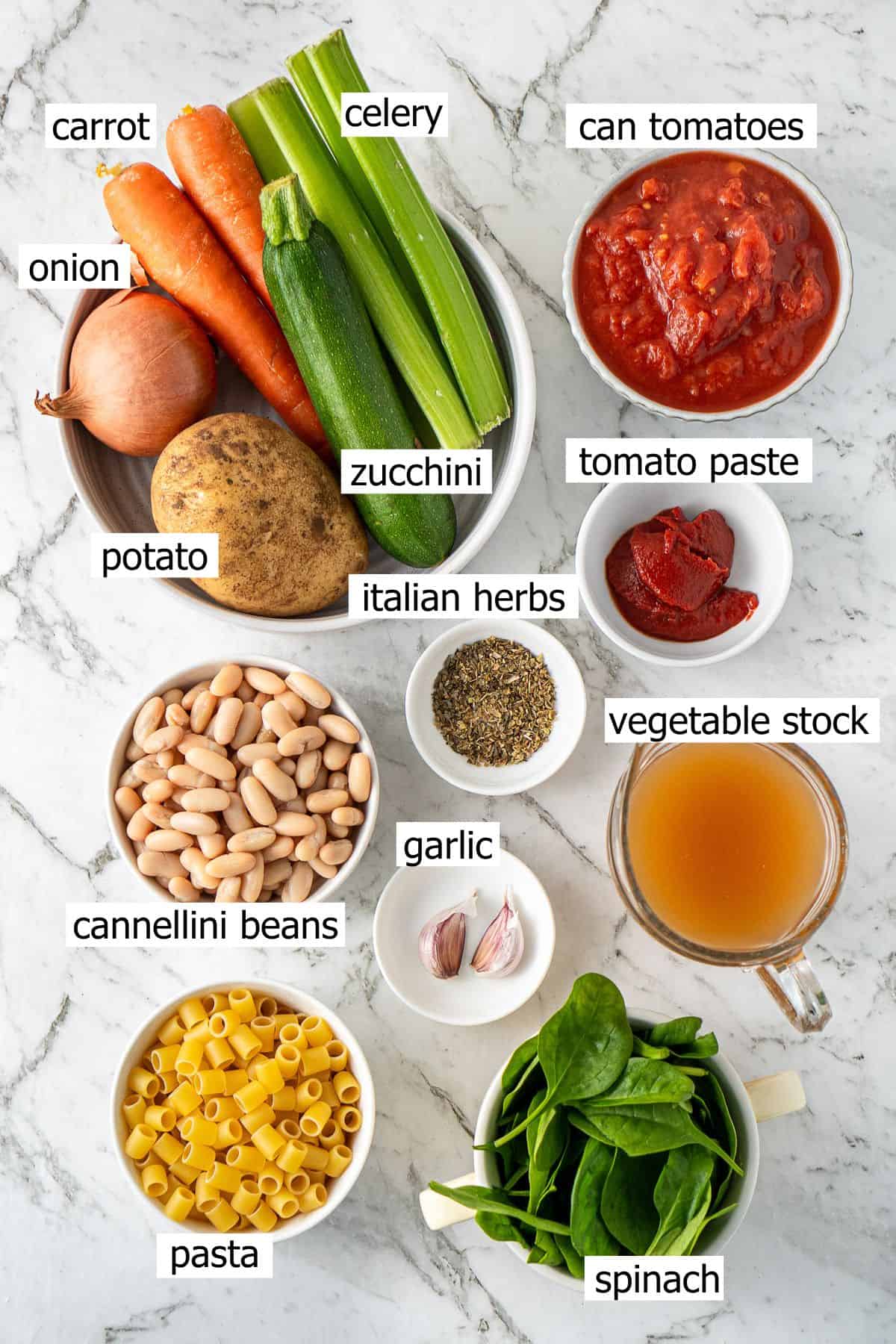 All ingredients needed to make vegetable minestrone laid out in small bowls.
