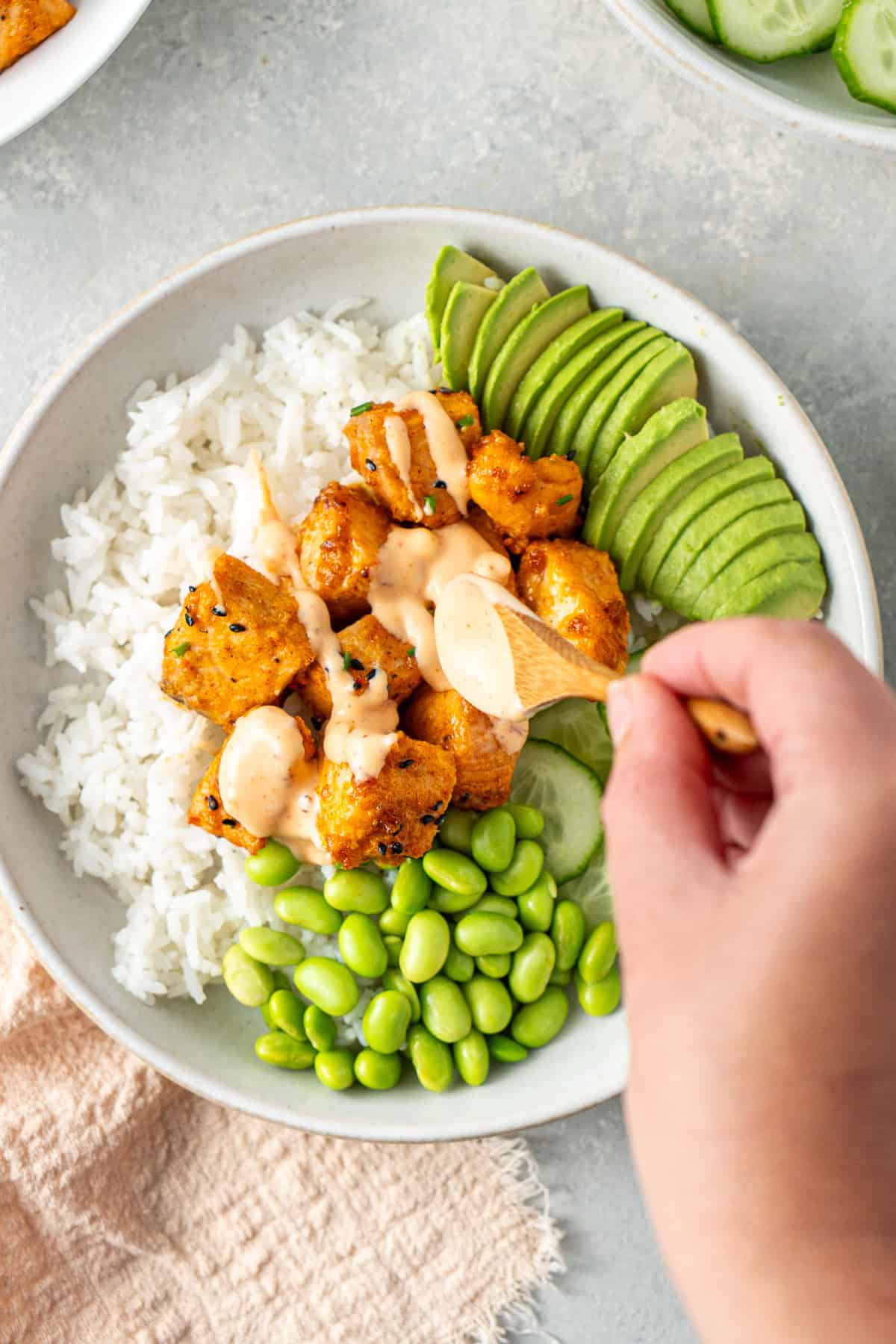 Spooning the bang bang sauce over the salmon rice bowl.