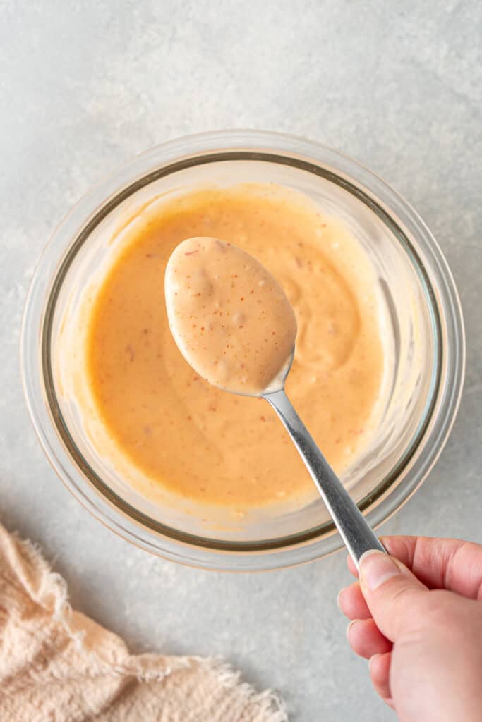 A spoon mixing together the bang bang sauce in a bowl.