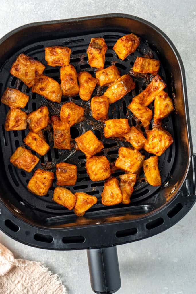 Cooked bang bang salmon in an air fryer basket.