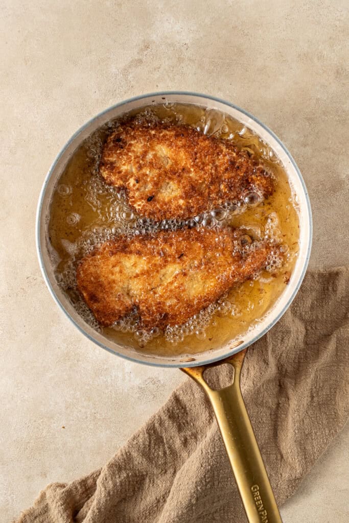 The chicken being fried until golden in the hot oil.