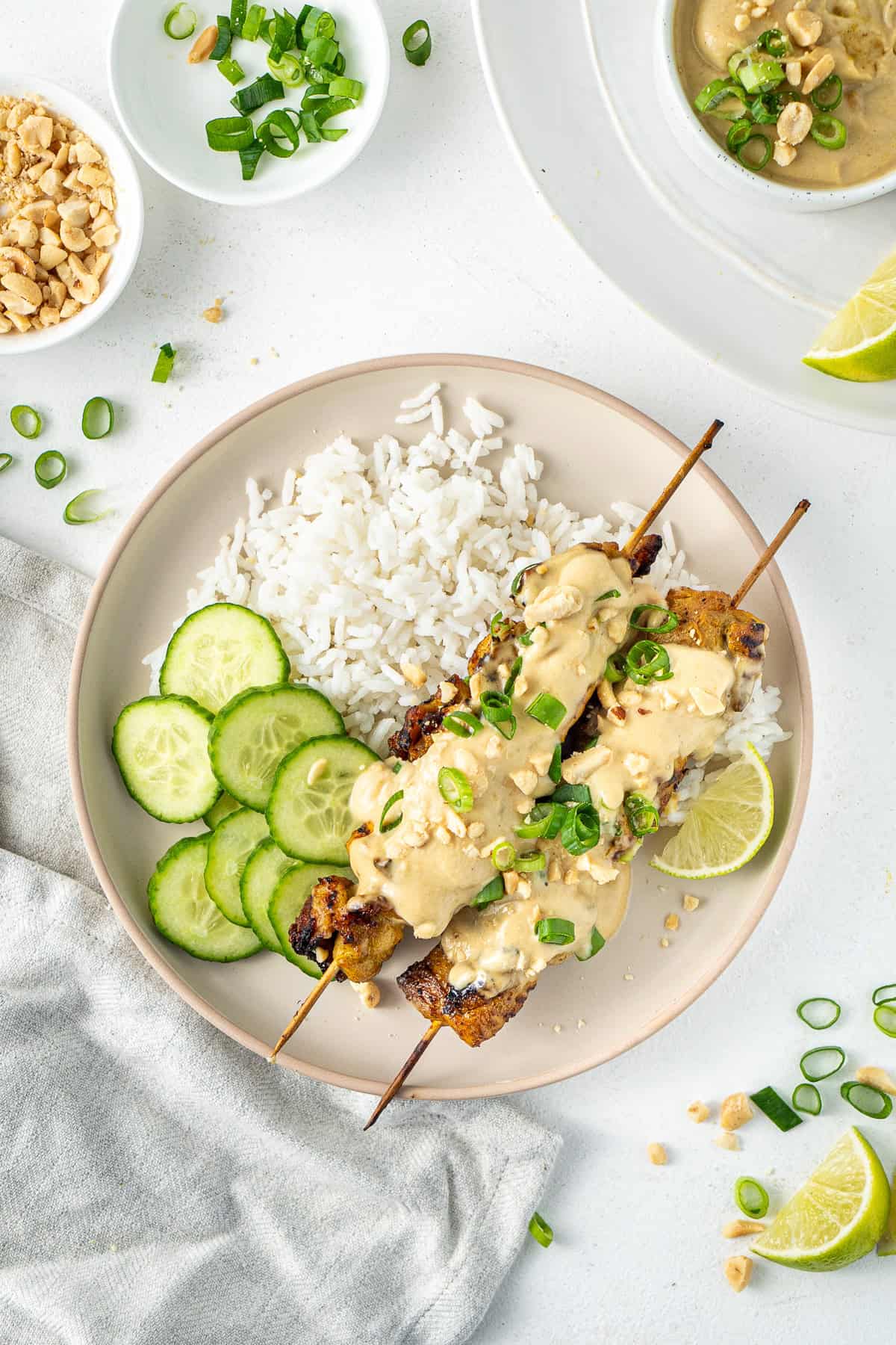 Satay chicken skewers served in rice with sliced cucumber.