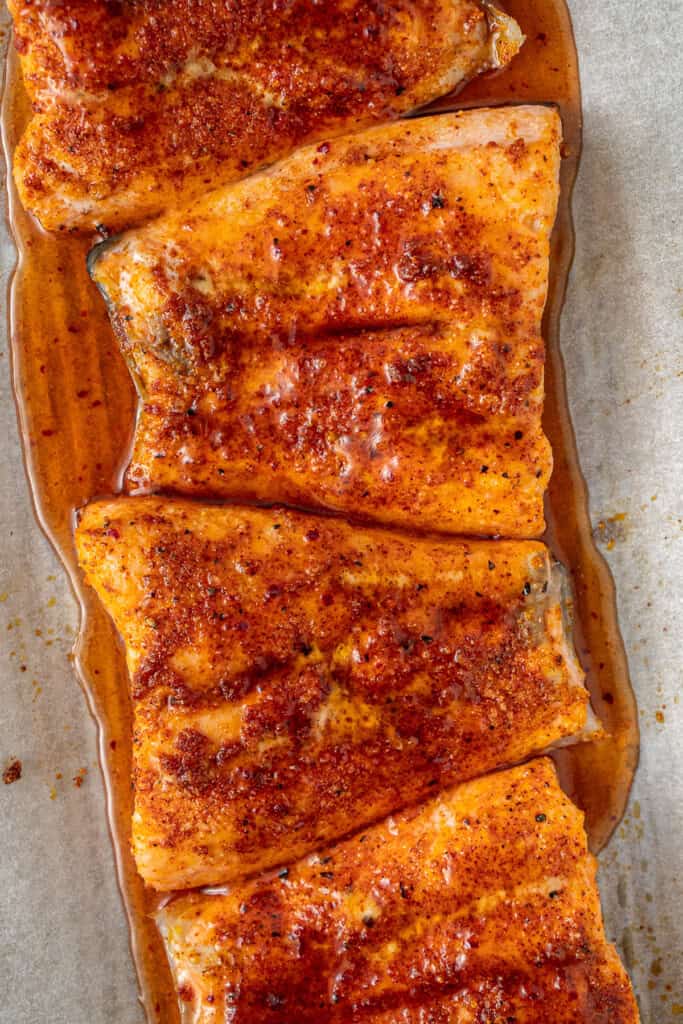 Hot honey drizzled over the baked salmon on a tray.