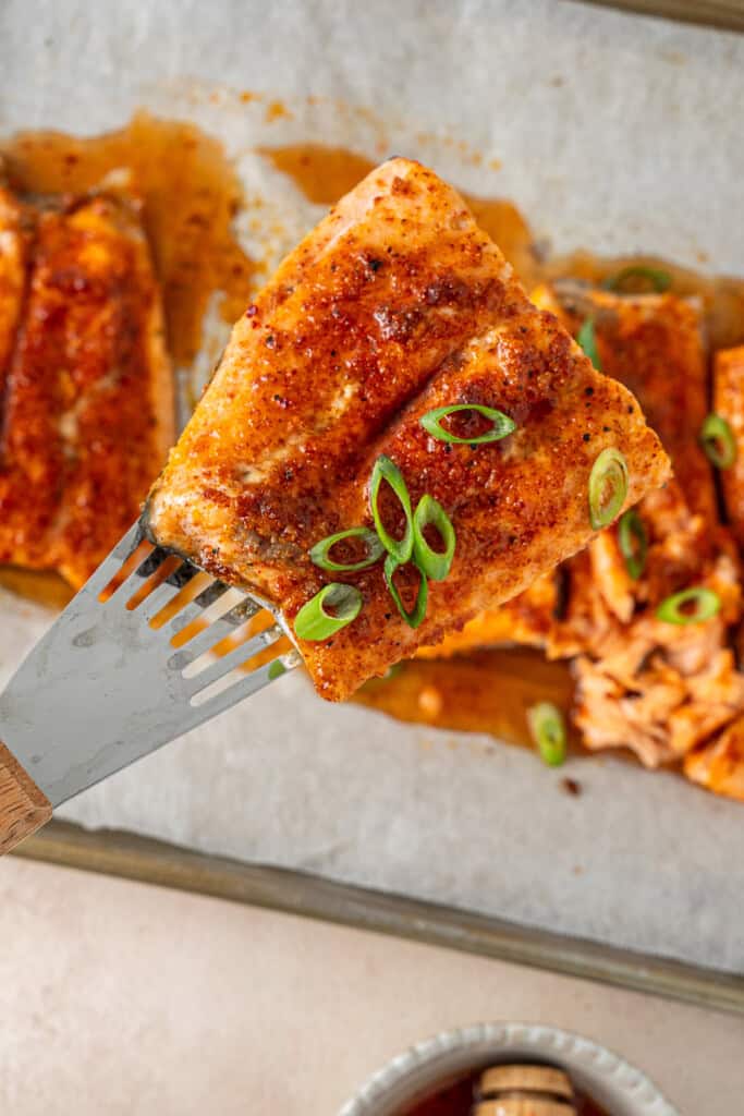 A spatula picking up a fillet of salmon.