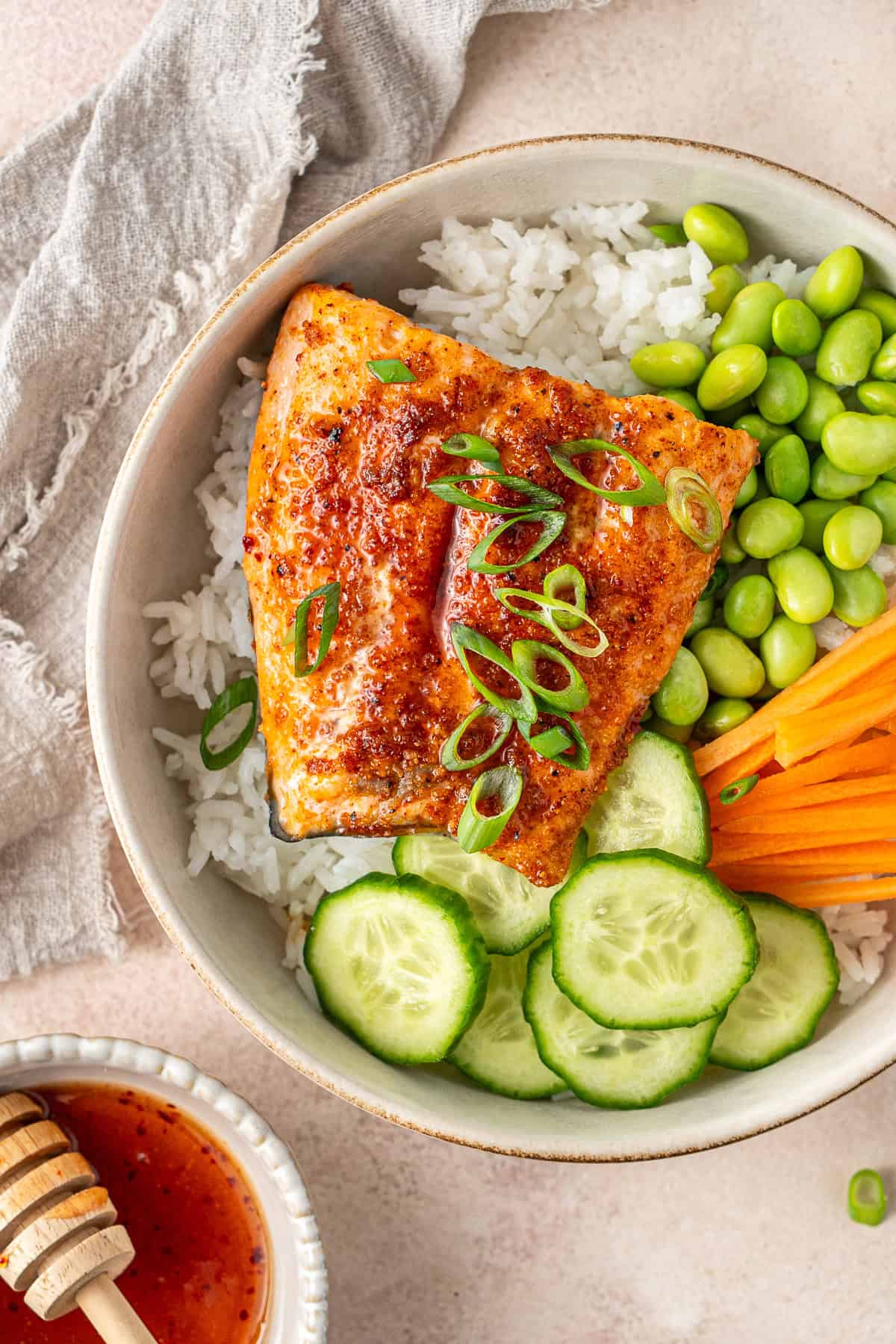 Close up of hot honey salmon in a rice bowl with spring onion as garnish.