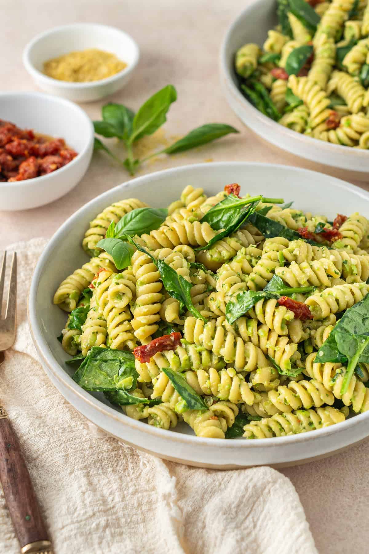 The served pea pesto pasta in bowls garnished with extra basil.