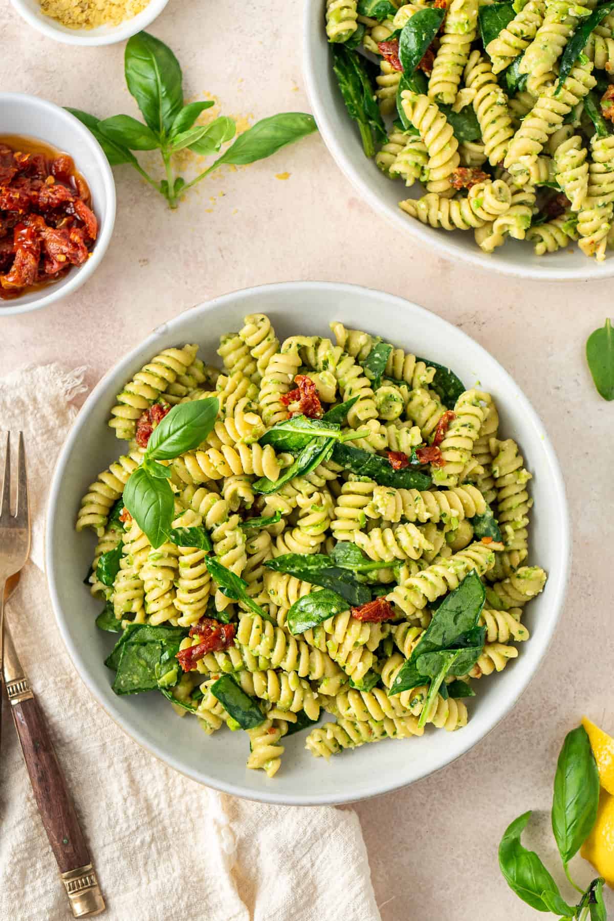 High protein pea pesto pasta served into bowls with spinach and extra basil.