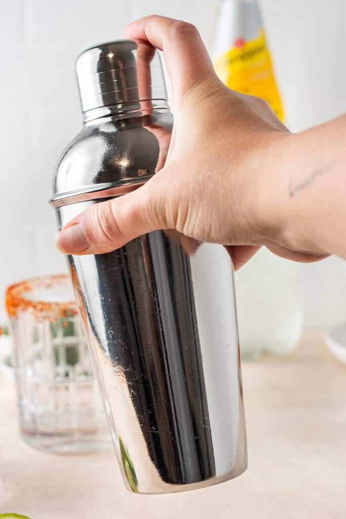 Shaking the mocktail in a silver cocktail shaker.