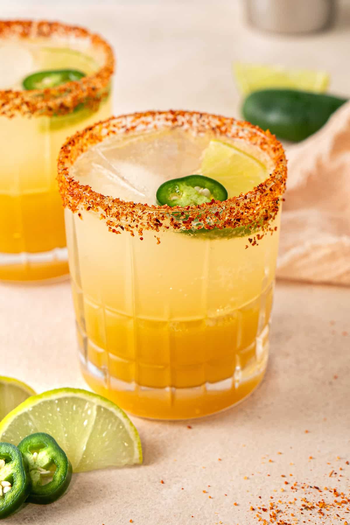 A spicy margarita mocktail with a tajin rim and fresh jalapeño slices. 
