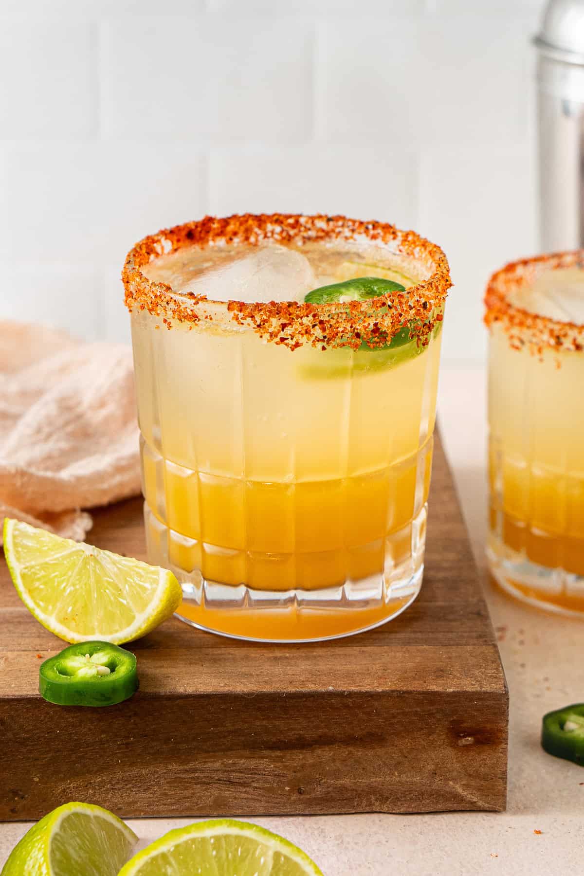 A spicy margarita on a wooden board with fresh lime and jalapeños. 