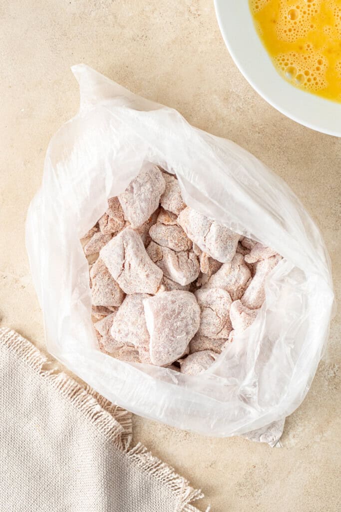 Tossing the chicken pieces in the cornflour mixture.