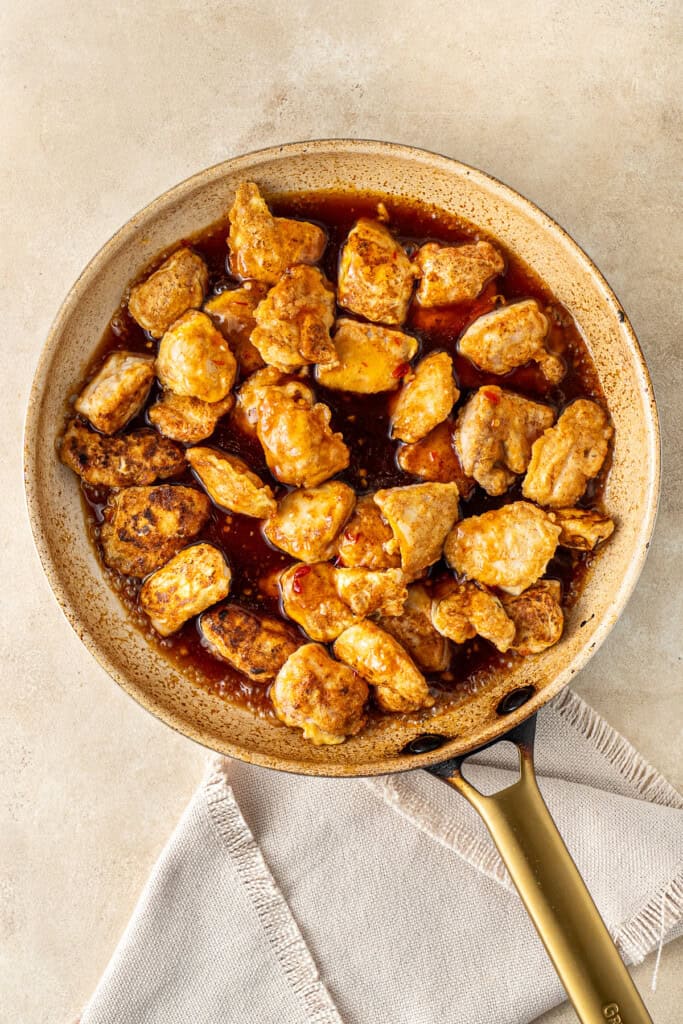 Adding the chicken and sauce to the frying pan.