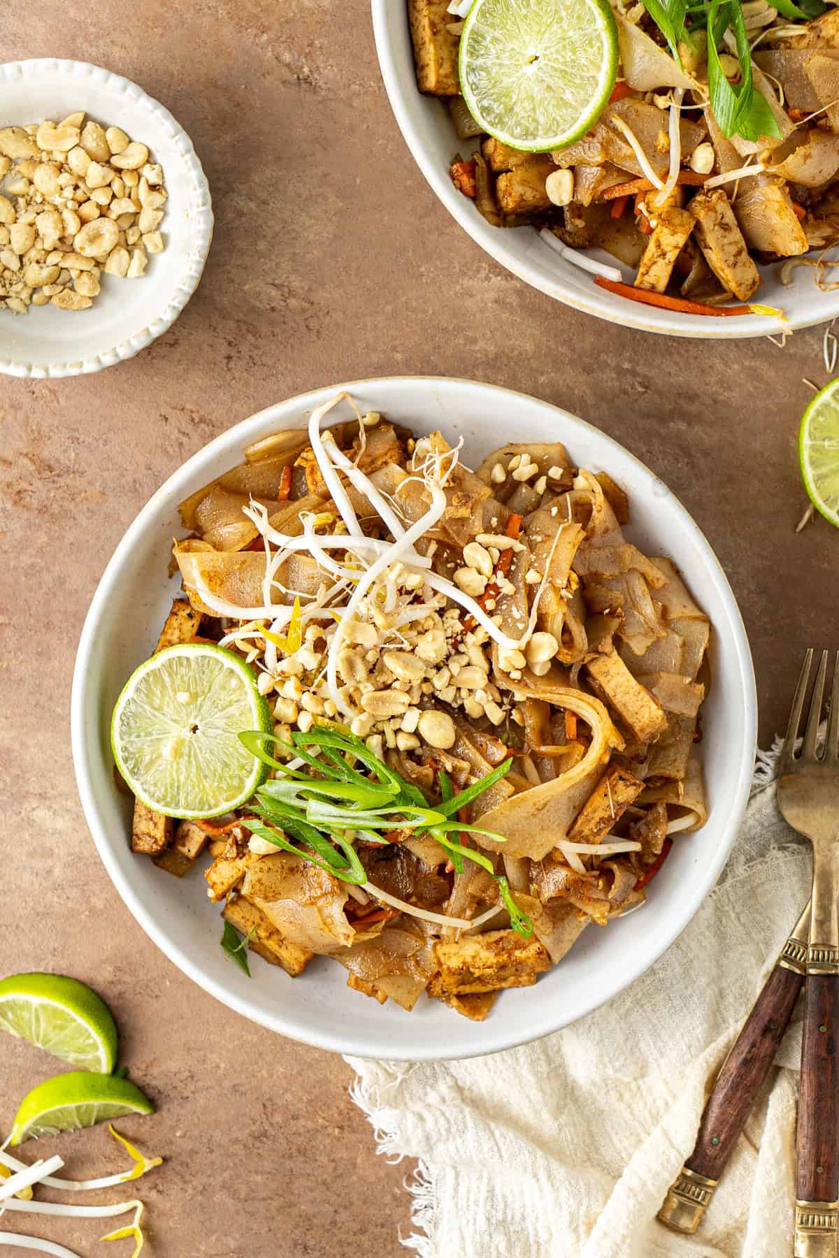 Tofu Pad Thai served into bowls with lime and crushed peanuts.