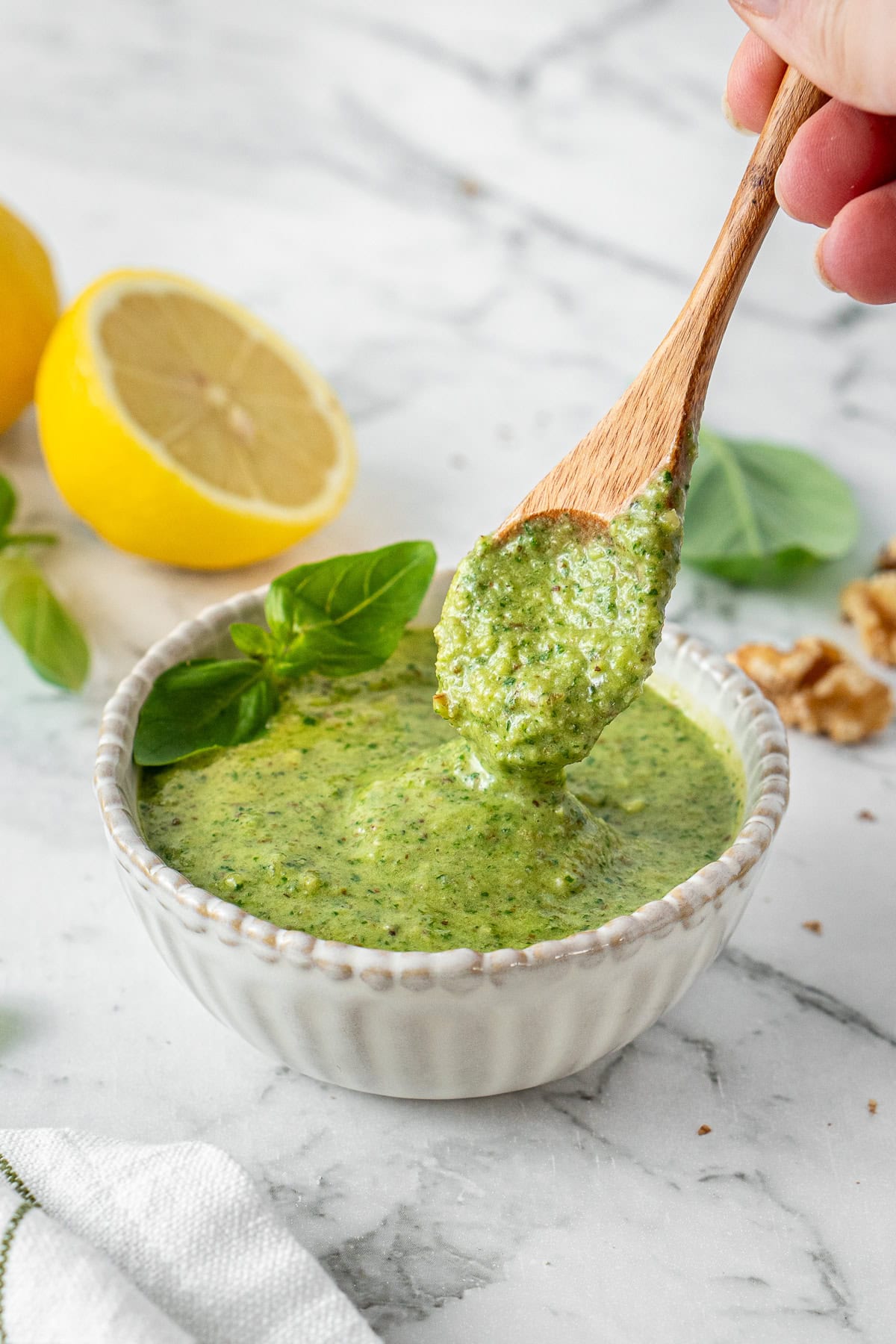 A spoon in a bowl of basil pesto.