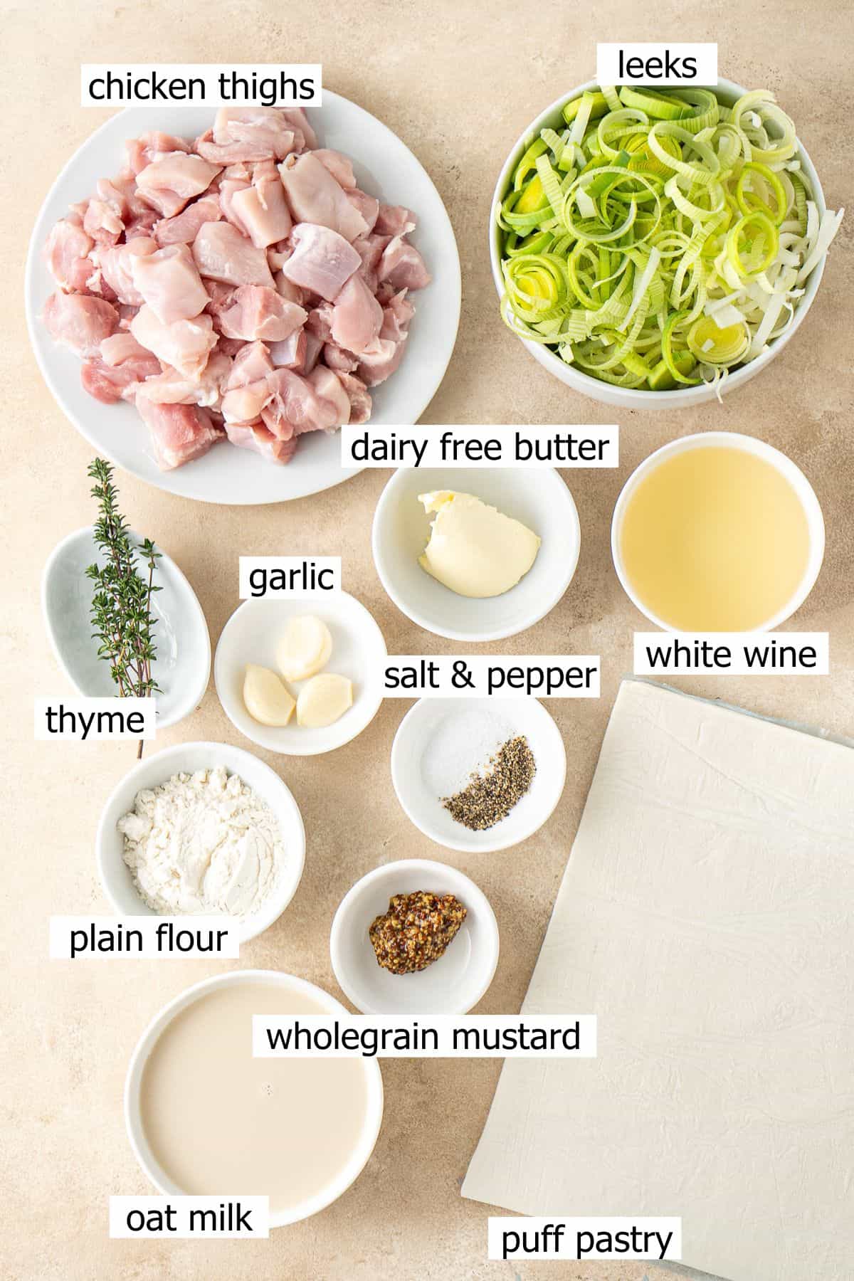 All ingredients needed to make a dairy free chicken and leek pie laid out in small bowls.