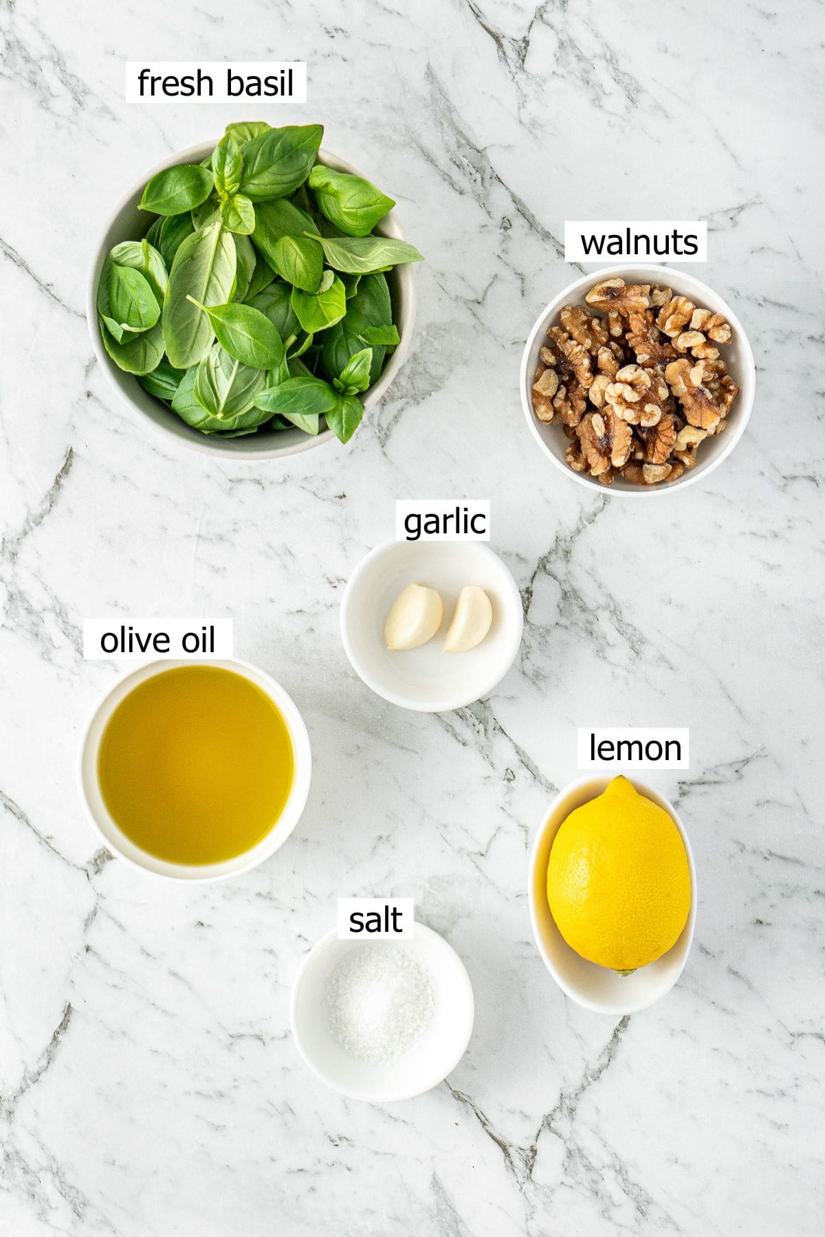 All ingredients needed for vegan basil pesto laid out in bowls.