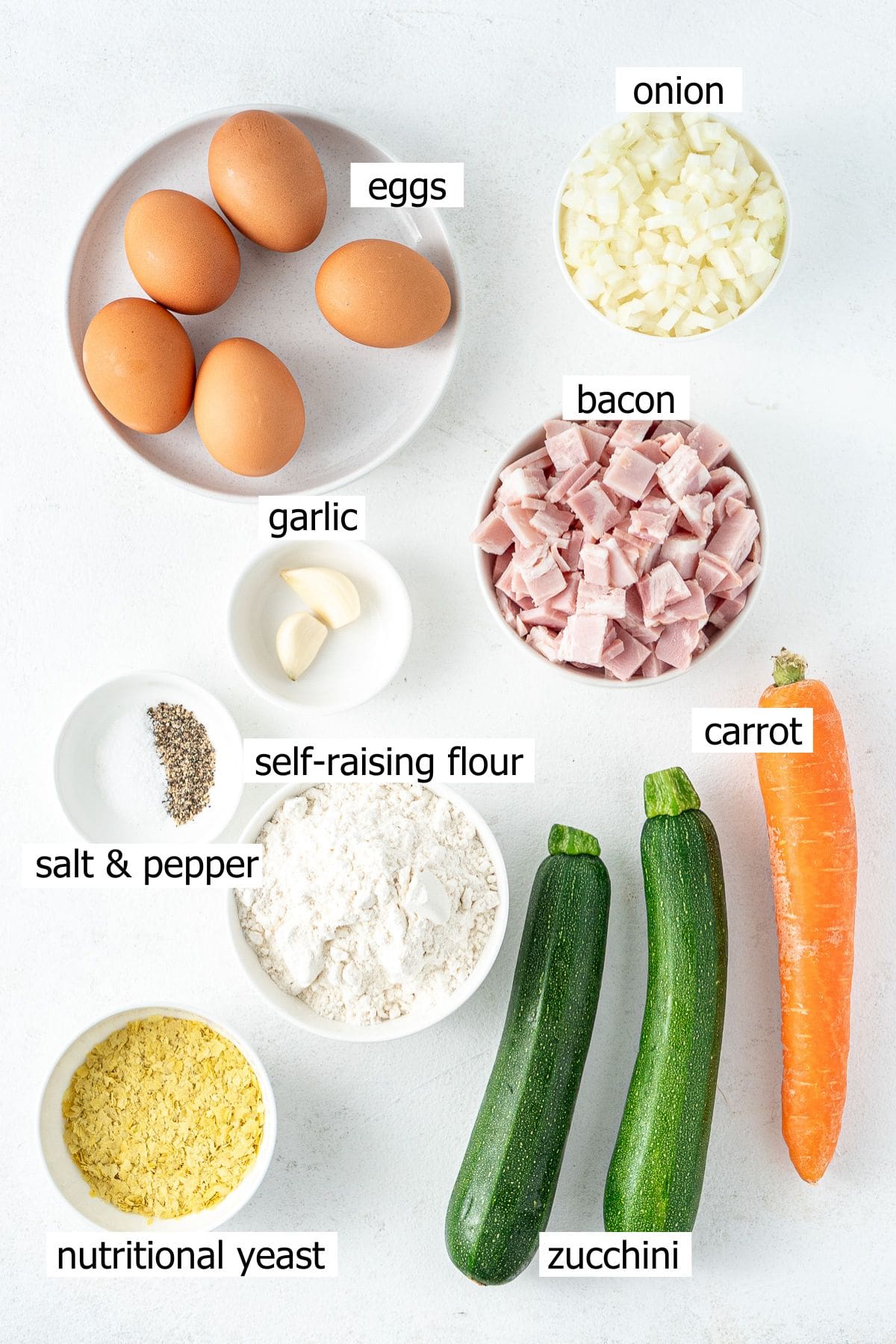 All ingredients needed to make easy zucchini slice laid out in small bowls.