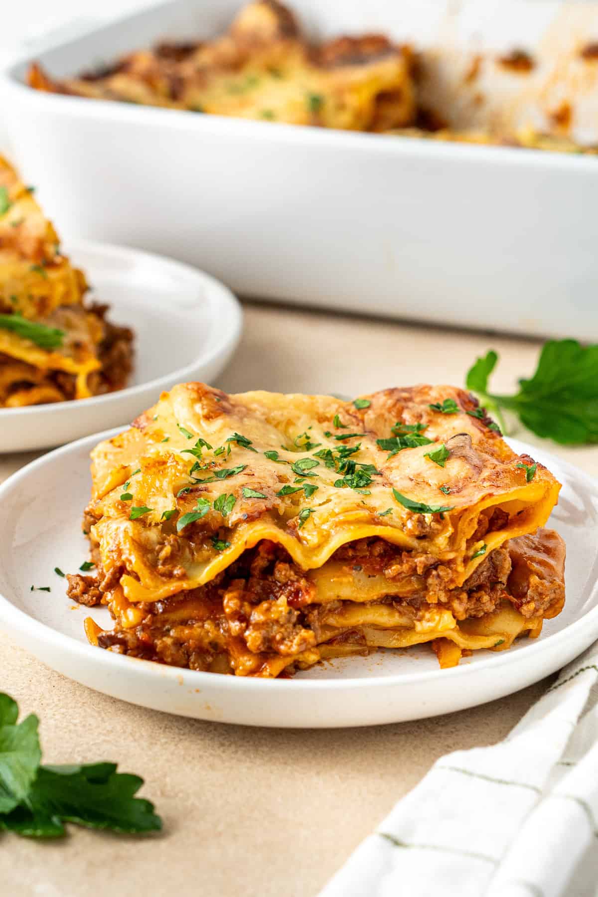 A slice of dairy free lasagna plated with fresh parsley.