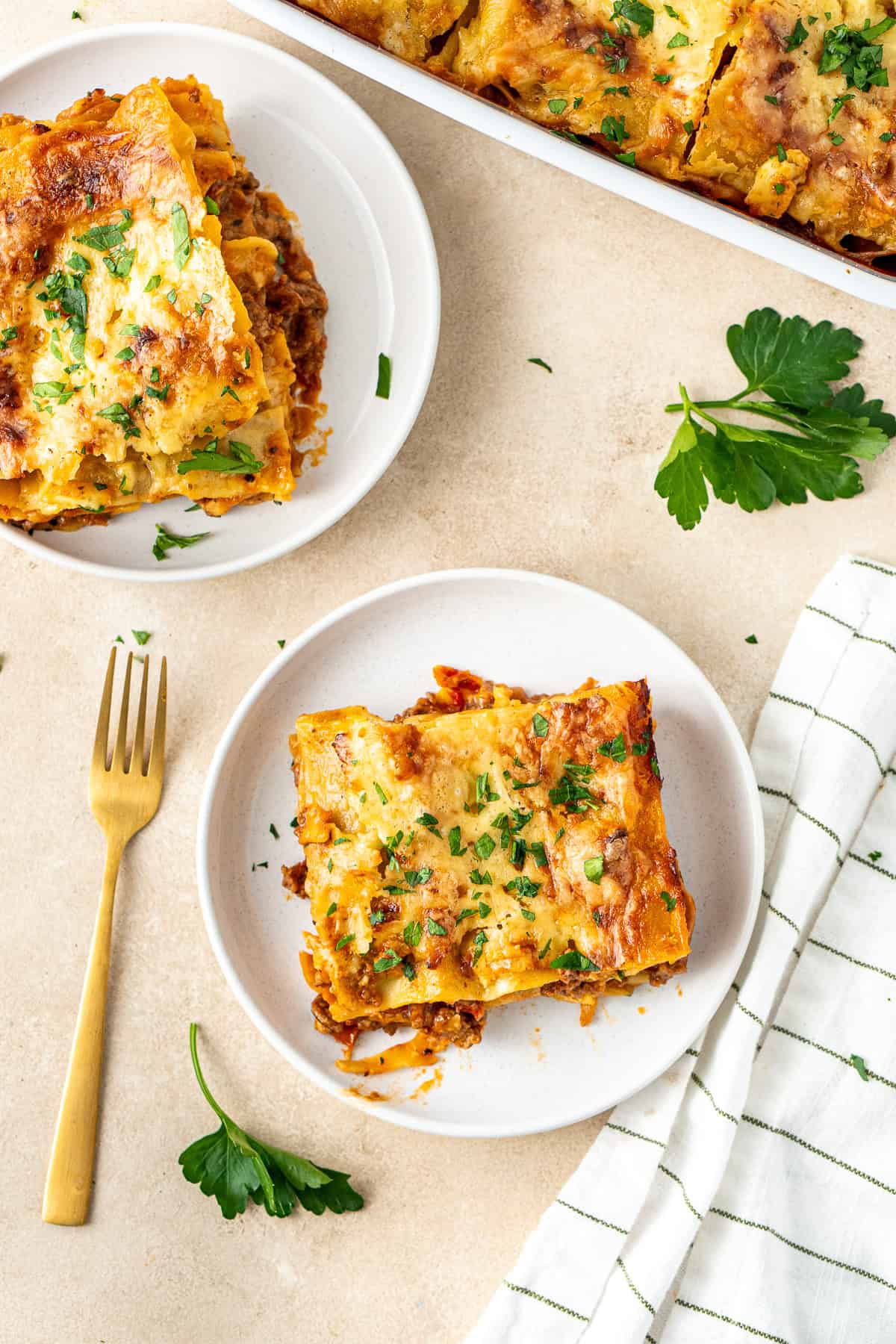 Dairy free lasagne served up onto plates with fresh parsley.